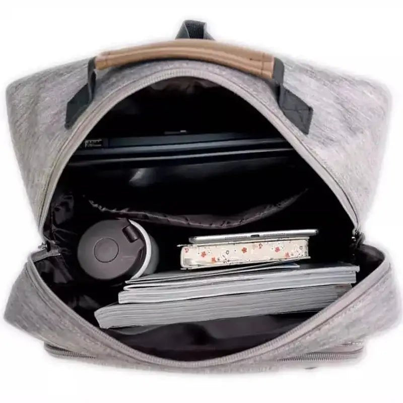 Sac à dos gris ouvert avec ordinateur portable, bouteille d’eau et livres pour femme