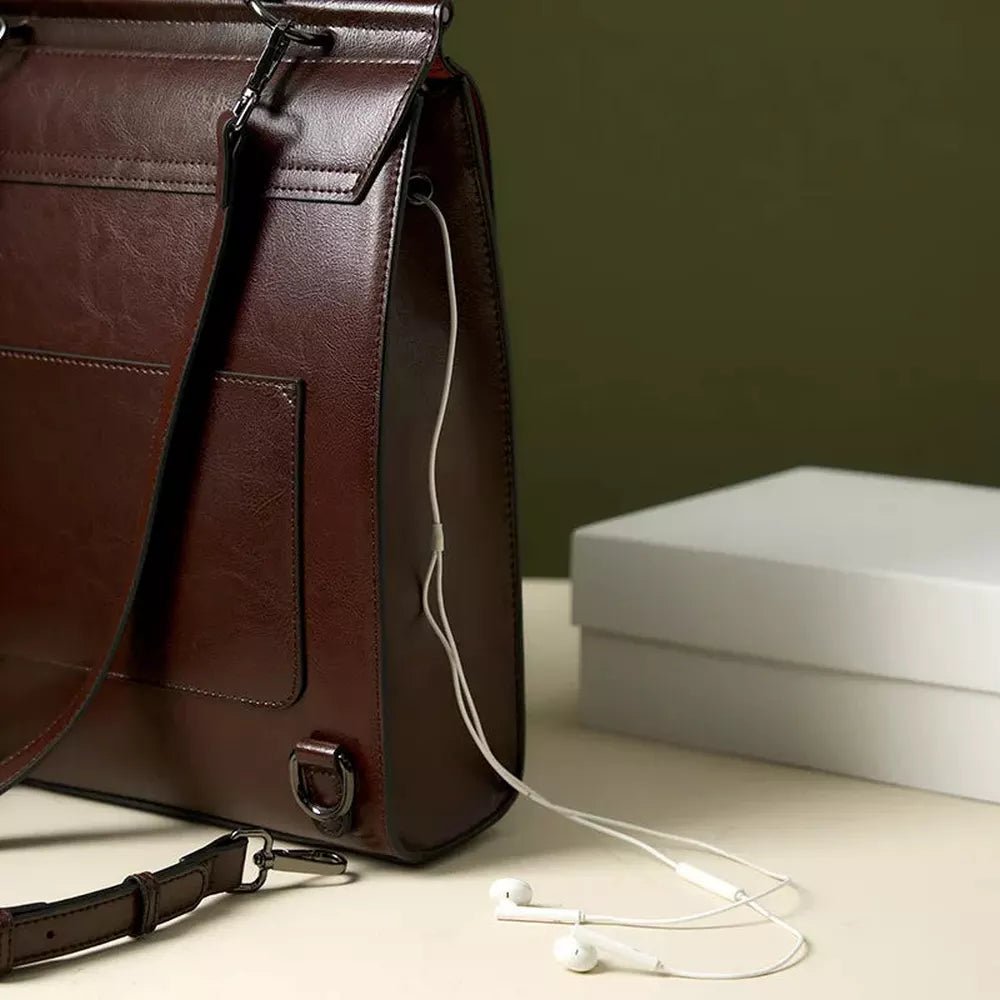 Sac à messenger en cuir vintage marron profond avec écouteurs blancs à proximité