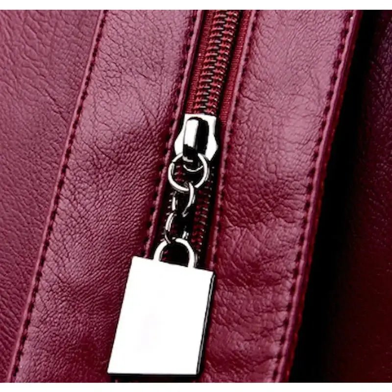 Zoom sur un sac à dos en cuir bordeaux avec fermeture éclair argentée pour femme tendance