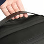 Main d’une personne tenant la sangle noire du sac à dos gris texturé SafePort