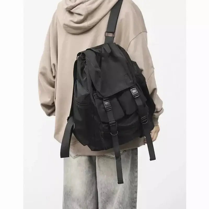 Sac à dos baroudeur homme en nylon noir avec rabat et nombreuses boucles de fermeture