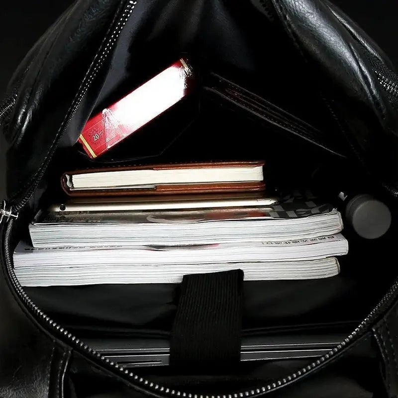 Sac à dos business homme cuir noir ouvert avec articles divers à l’intérieur