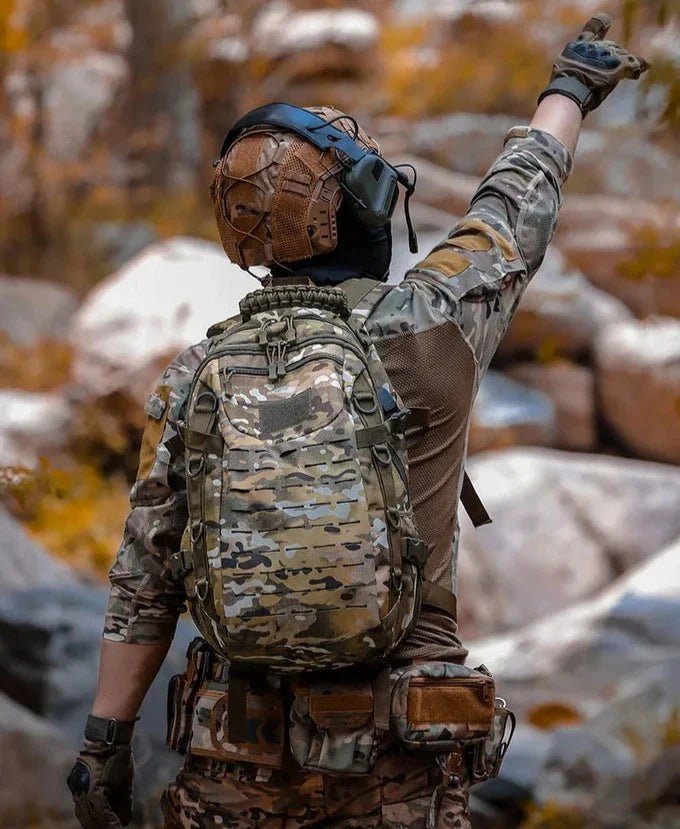 Person en équipement camouflage avec sac à dos d’airsoft 35L et casque pointant vers le haut