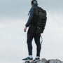 Person de dos portant un sac à dos de voyage avec compartiment isotherme sur terrain rocheux