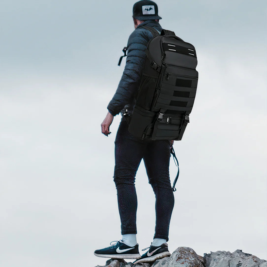 Person de dos portant un sac à dos de voyage avec compartiment isotherme sur terrain rocheux