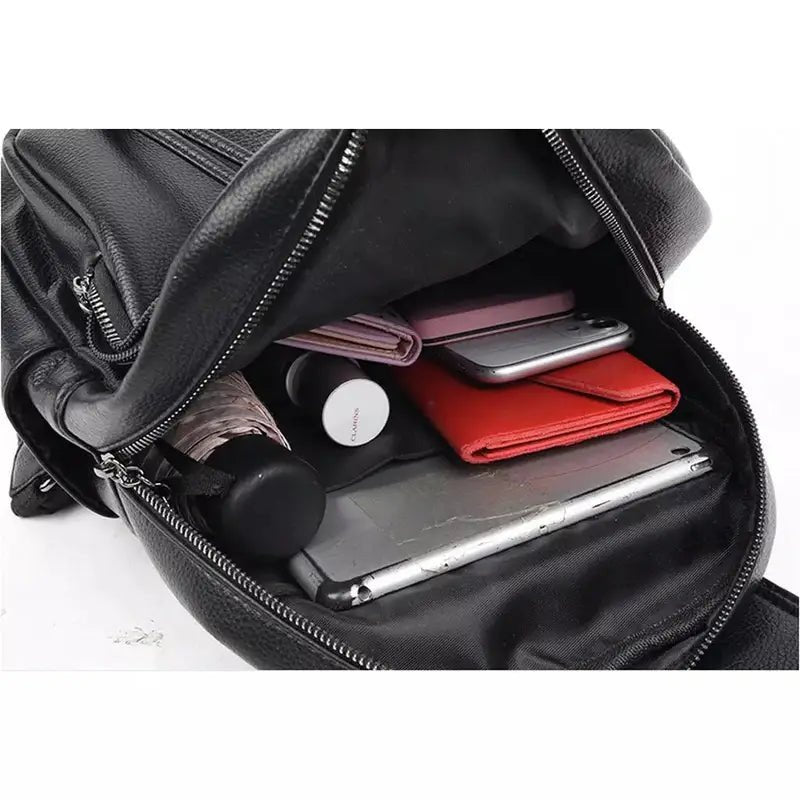 Sac à dos en cuir noir pour femme avec compartiment principal ouvert et objets personnels