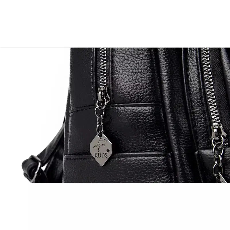 Sac à dos en cuir noir pour femme avec texture, deux compartiments zippés et pendentif en métal