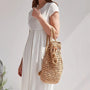 Femme portant une robe blanche avec un sac à dos en paille chic et tressée