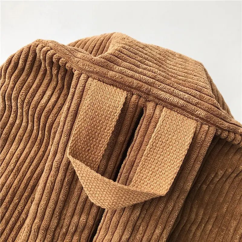 Détail en gros plan du tissu en velours marron avec des bandoulières tissées pour Sac à dos en velours