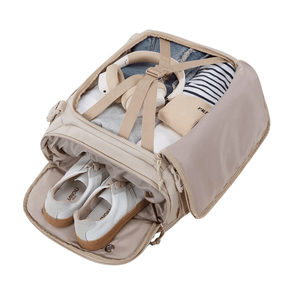 Sac à dos femme voyage cabine avec sac beige ouvert contenant vêtements, écouteurs et chaussures