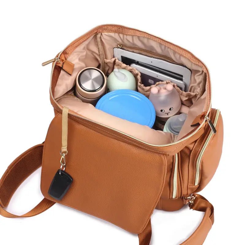 Sac à dos à langer en cuir marron ouvert avec compartiments organisés