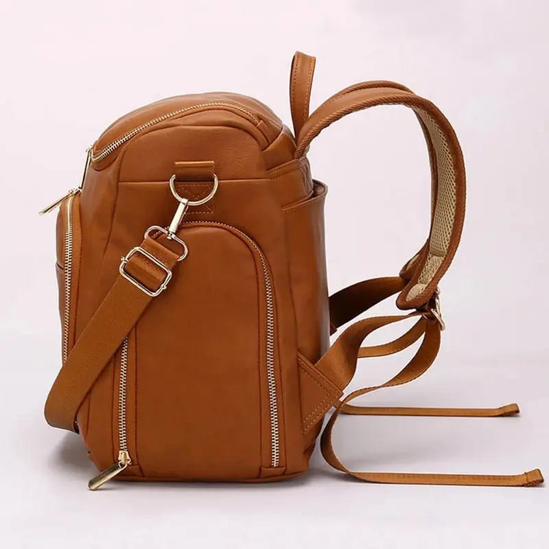 Sac à dos à langer en cuir marron avec multiples poches zippées et bretelles ajustables