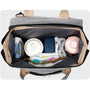 Sac à dos à langer extensible gris avec essentiels pour bébé comme formule, couches et biberon