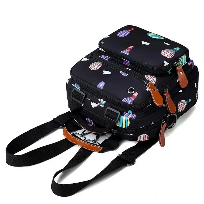 Sac à dos à langer noir avec motifs colorés abstraits et plusieurs compartiments zippés