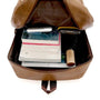 Sac à dos ordinateur homme en cuir marron rempli de livres et d’objets personnels