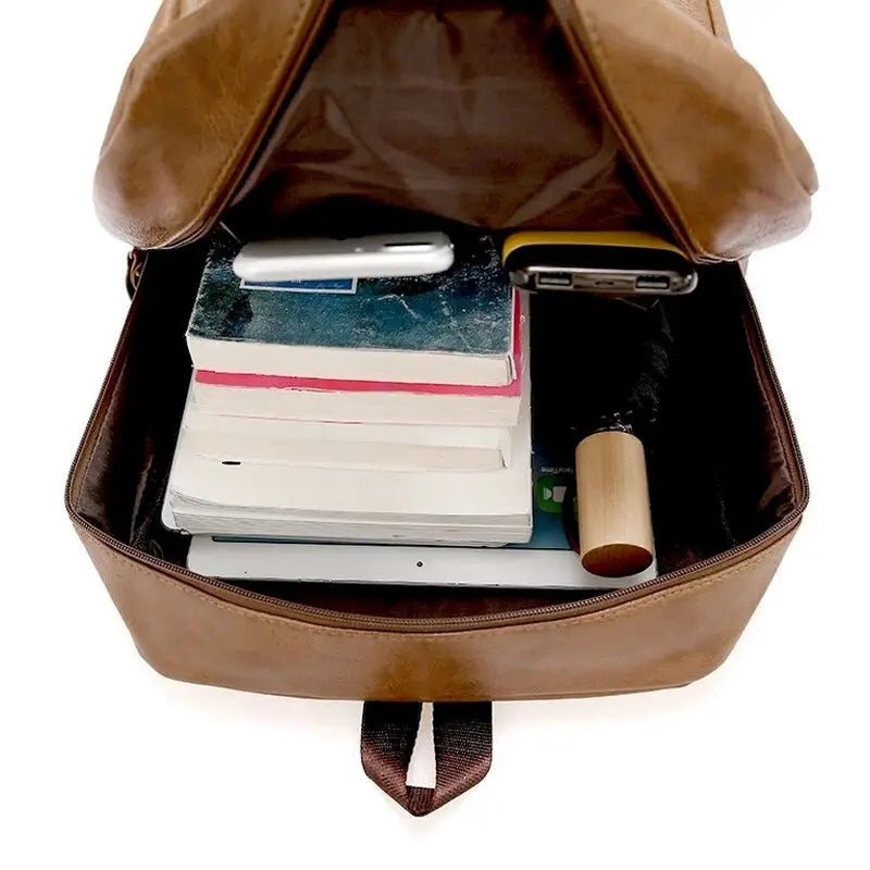 Sac à dos ordinateur homme en cuir marron rempli de livres et d’objets personnels