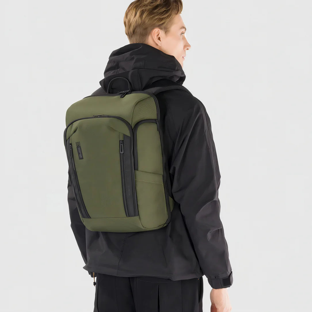 Sac à dos PC portable ouverture 180° porté par une personne en veste noire et sac olive