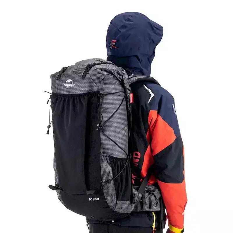 Homme portant un sac à dos de randonnée 60L gris et noir à motif carreaux