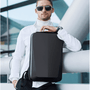 Sac à dos rigide ultra-plat antivol noir avec poignée tenue par un homme en turtleneck blanc