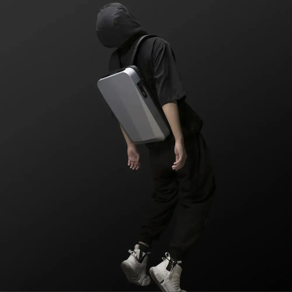 Person portant un sac à dos rigide noir et gris clair Atom antivol ultra-plat