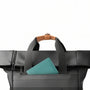 Sac à dos roll top noir avec tote bag noir, carnet teal et poignée en cuir marron