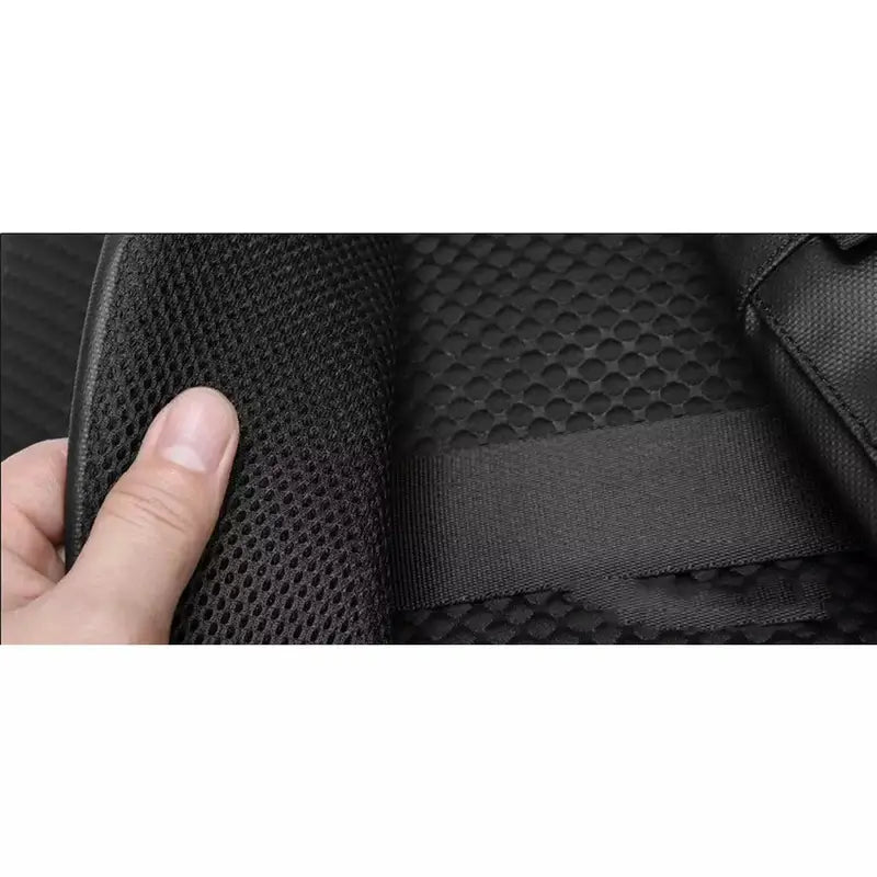 Main tenant touchant un tissu en maille noire avec un sac à dos voyage ordinateur en arrière-plan